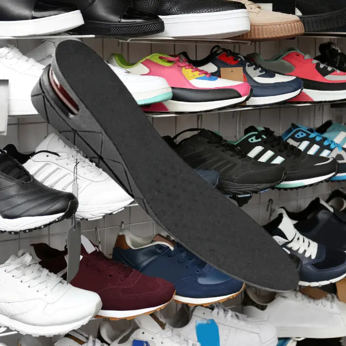 Adjustable height insoles floating in front of athletic sneaker display in a retail shoe store.