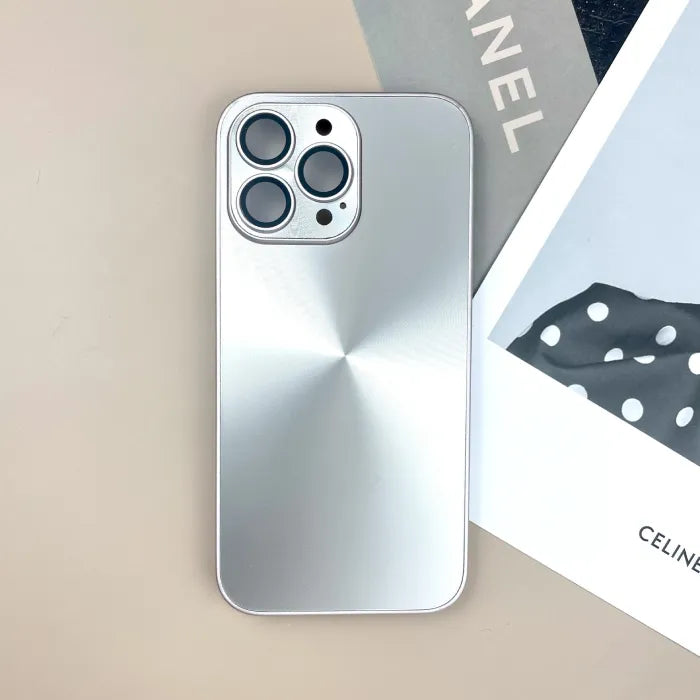 Silver anti smudge iPhone case with brushed metallic look on beige desk next to fashion magazine.