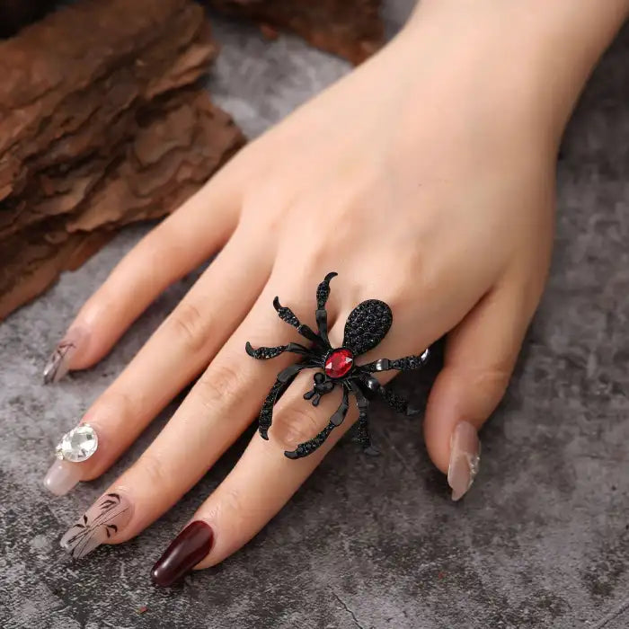 Blackwidow Spider rings with black body and red gem center styled on manicured hand