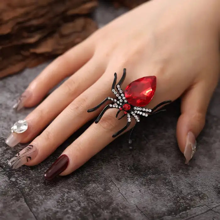 Blackwidow Spider rings with large red gemstone and crystal accents on hand with designer nails