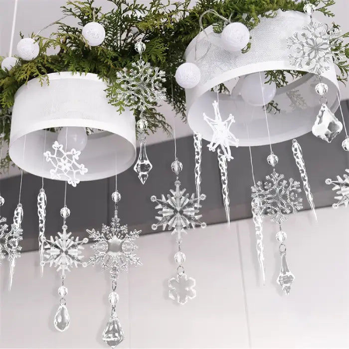 Elegant crystal snowflake ornaments hanging from white lampshades with greenery and white baubles for Christmas decor