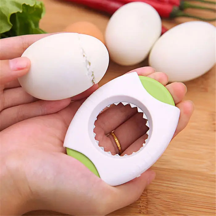 green-accented kitchen egg opener breaking a white egg over a wooden surface