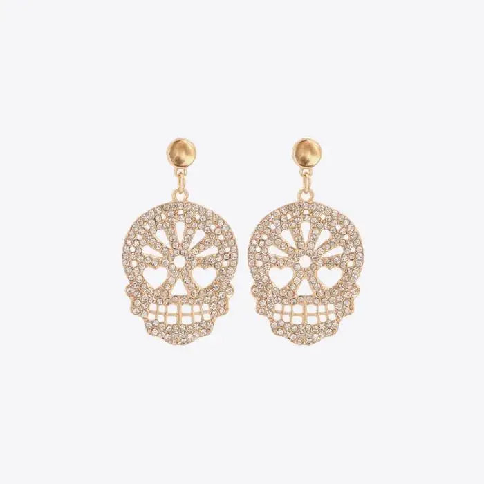 Gold skull-shaped dangle earrings adorned with clear rhinestones on a white background.