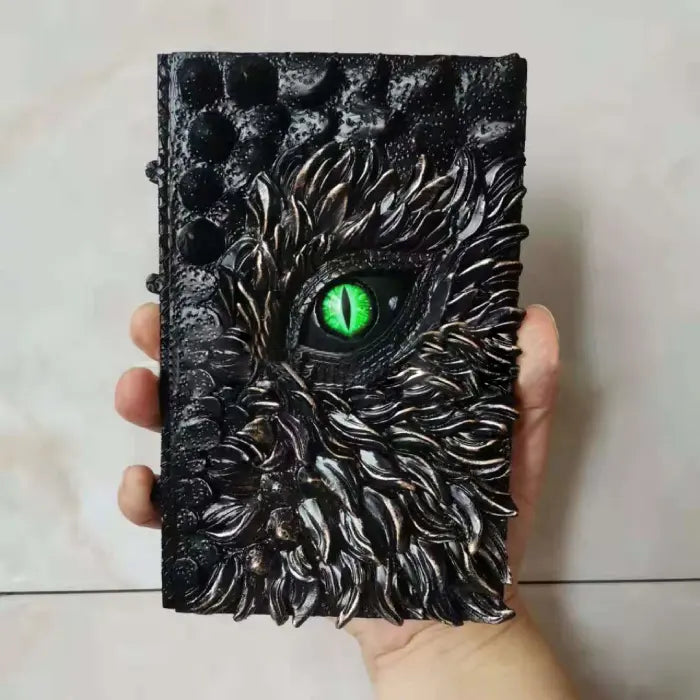 Halloween Decor book of dragons with glowing green reptilian eye held in hand for scale.