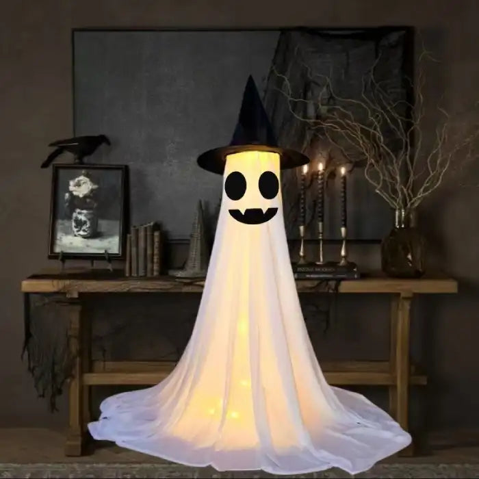 Halloween Ghost Yard Decor with vampire fangs and smiling face glowing in dark spooky setup.