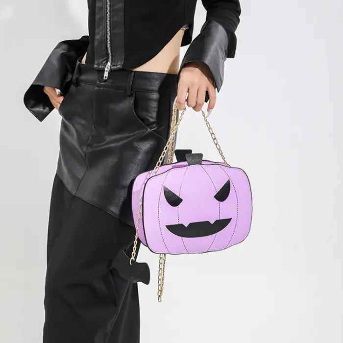 Halloween Pumpkin Head bag in purple with gold chain strap held by woman in black outfit