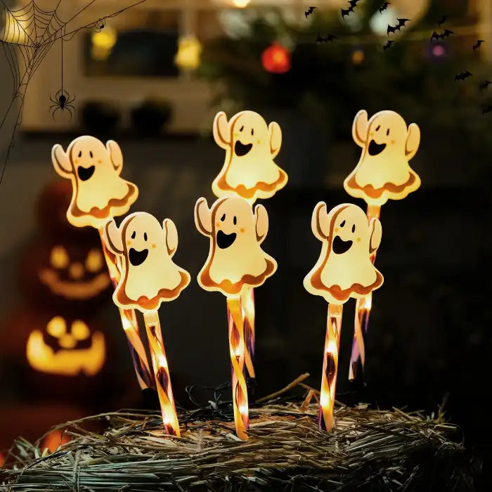 Halloween Pumpkin LED lights with cute ghost decorations glowing on hay in festive Halloween setting