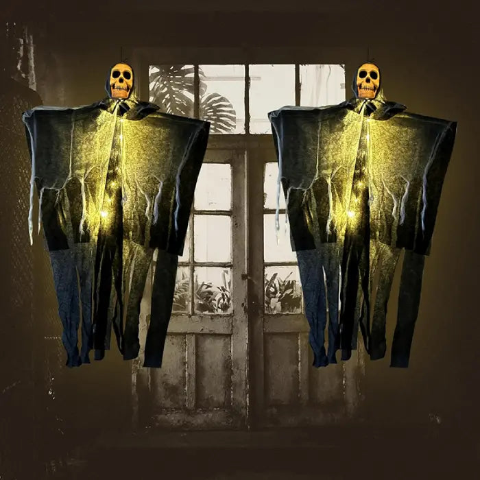 Two glowing halloween skeleton ghosts with hanging fabric in front of eerie backlit window for decor scene.