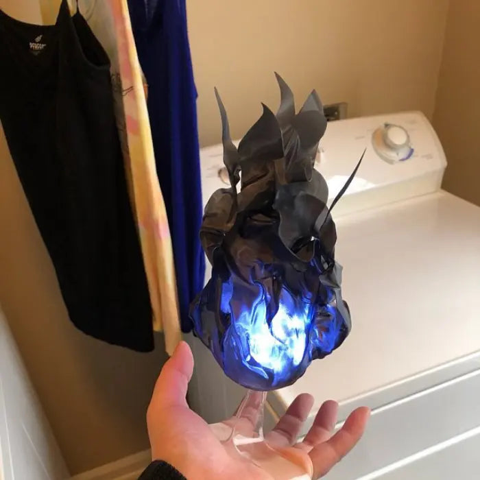 Handheld fireball prop with black and blue glowing flame effect held over a white dryer.