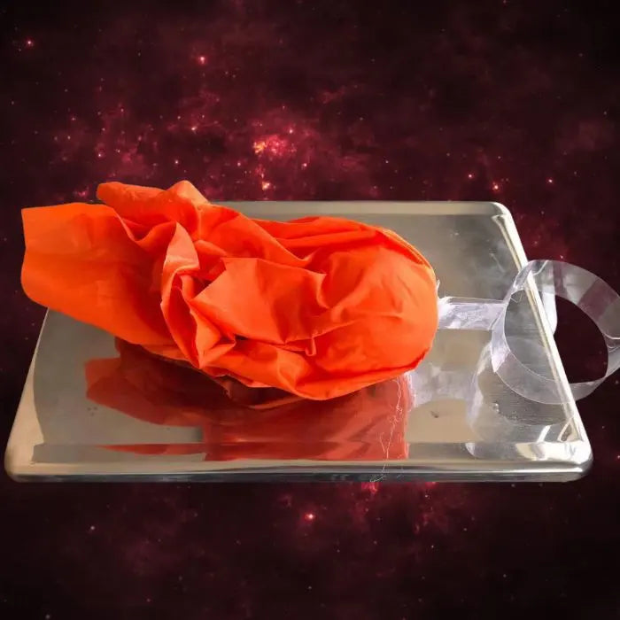 Handheld fireball prop orange fabric material being weighed on scale, showing 113.7g measurement.