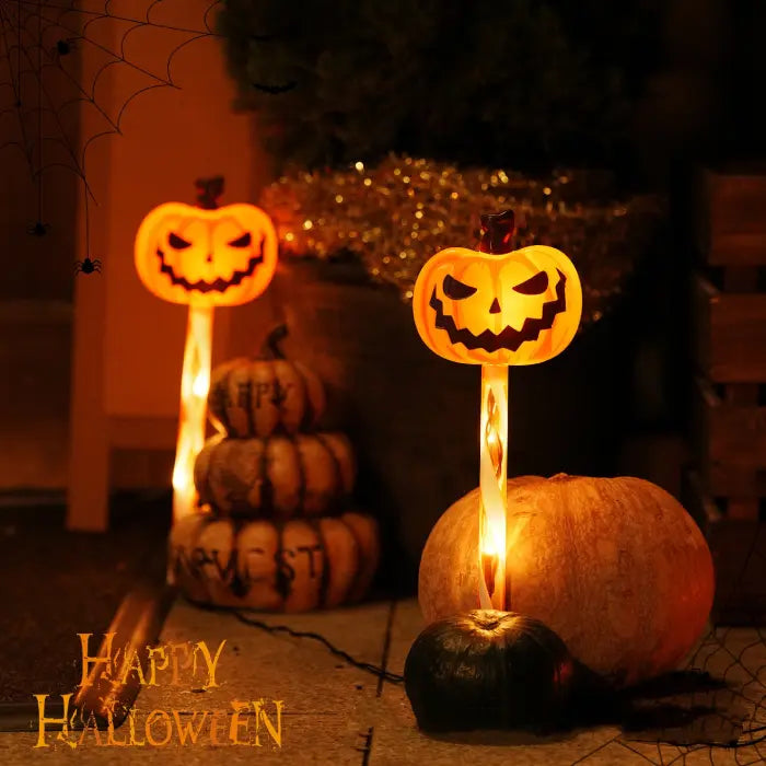 Halloween-themed decorations with jack-o'-lantern faces and stacked pumpkins on a dark background.
