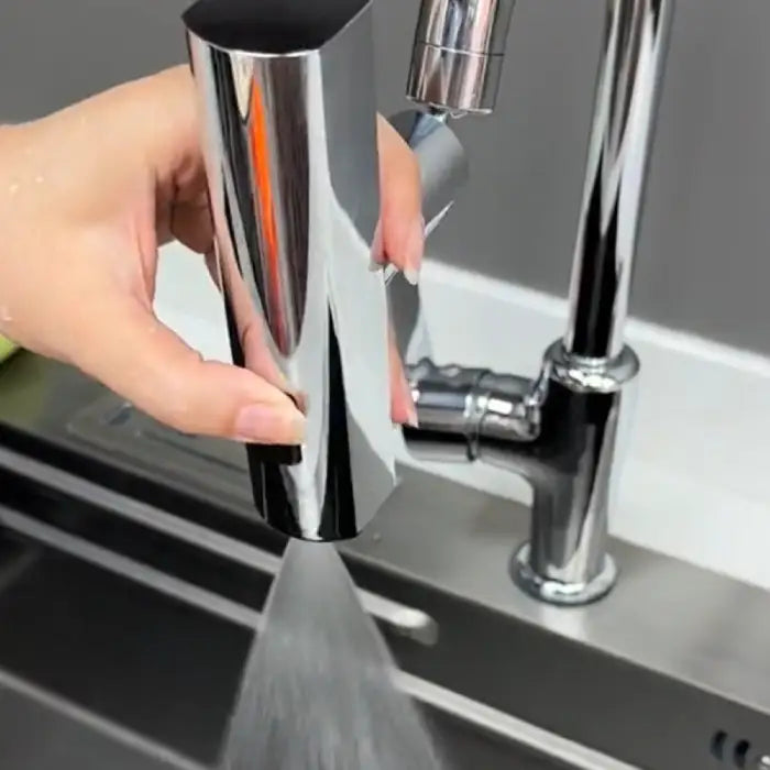 Closeup of kitchen faucet in sweep mode spraying water at sink for easy rinsing.