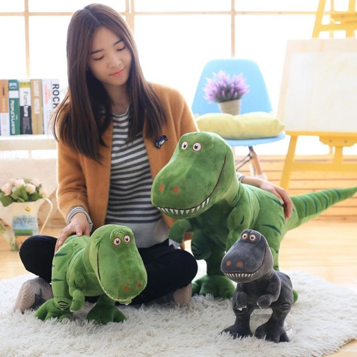 Plus dinosaur toy in three sizes shown with girl sitting on floor in bright room