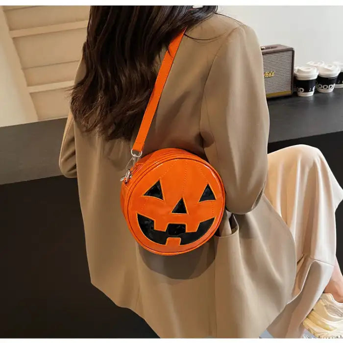 Orange Pumpkin Head Purse worn as a shoulder bag with black jack-o-lantern face design.
