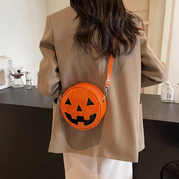 Pumpkin Head Purse in vibrant orange faux leather worn with tan blazer for Halloween outfit.