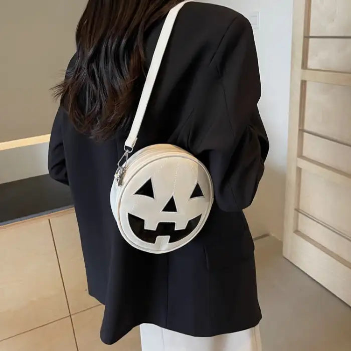 Pumpkin Head Purse in white faux leather worn as crossbody over a black blazer.