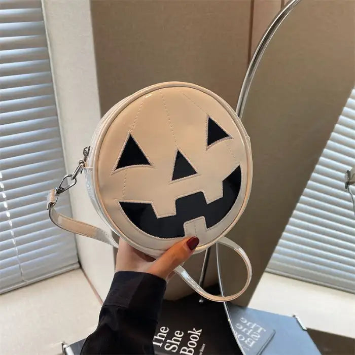 Pumpkin Head Purse in smooth white leather with black face, shown handheld near daylight window.