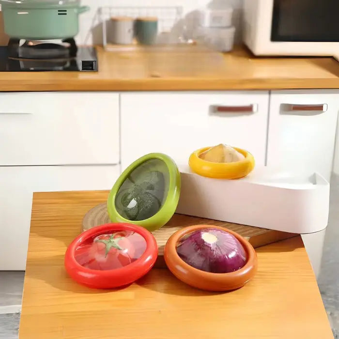 reusable fruit and vegetable storage containers with color-coded lids holding avocado, tomato, onion and lemon on wooden counter