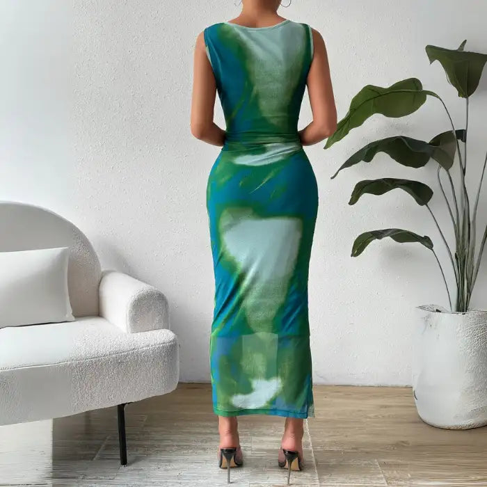 Back view of a green ruched maxi form-fitting dress with a sleeveless design and vibrant watercolor pattern.