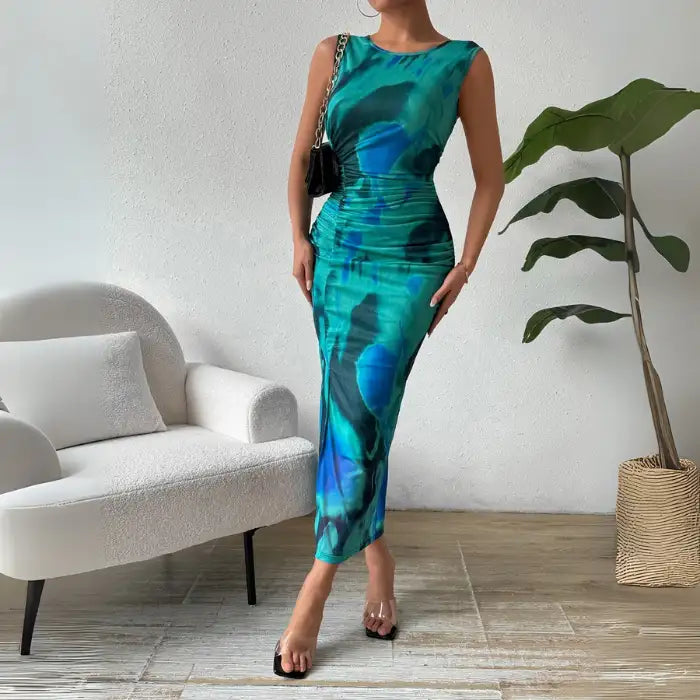 Blue ruched maxi form-fitting dress featuring a sleeveless design, side slit, and flattering silhouette.