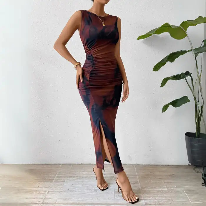 Brown ruched maxi form-fitting dress with a sleeveless design, side slit, and elegant tie-dye pattern.