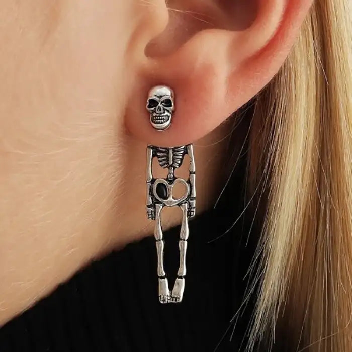 Skeleton earrings with full-body dangling design worn on ear, silver tone, perfect for Halloween style.