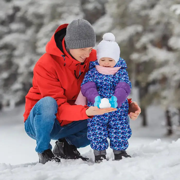 Snowball makers used by toddler and parent in winter snow for fun outdoor bonding activity