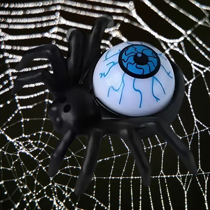Blue-eyed spider candle crawling on dew-covered Halloween spiderweb.