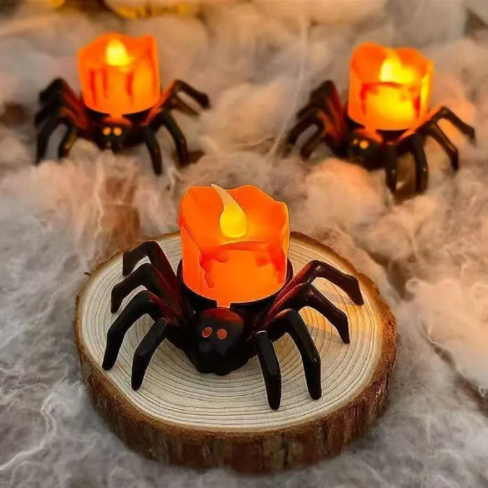 Trio of orange spider candles on web-like surface with cozy Halloween lighting.