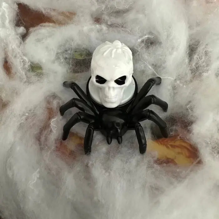 Spider candle with creepy white skull top on Halloween web background.