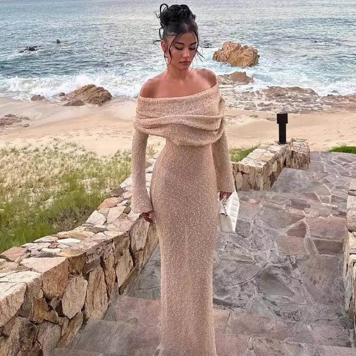 Women's one-shoulder long-sleeve knitted vacation dress in beige styled for a luxury beach resort.