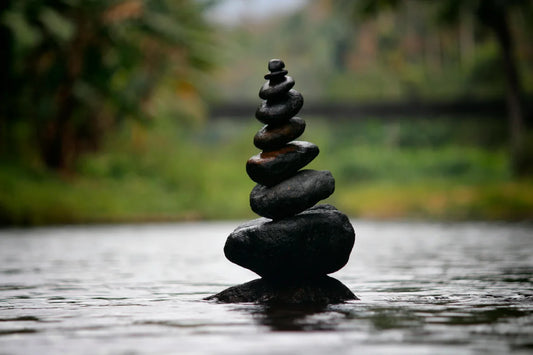  Balanced stack of smooth black stones in water with blurred natural background