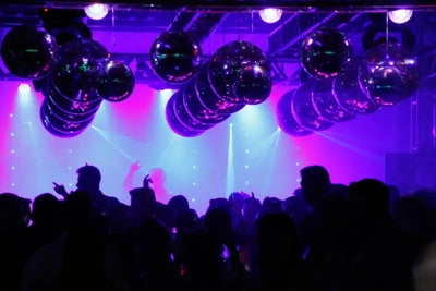 prom dresses for prom night venue with purple lighting, disco balls illuminating dance floor filled with celebrating students