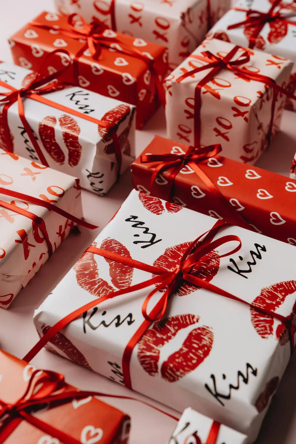 Beautiful Valentine's gift ideas with red and white wrapping featuring hearts and kiss patterns tied with red ribbons.