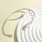Silver bracelet on a white plate with a beige background