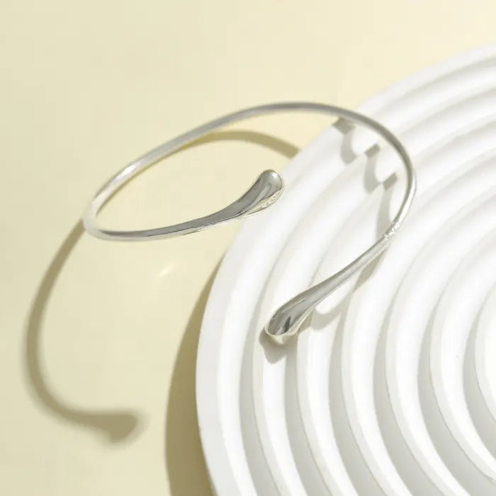 Silver bracelet on a white plate with a beige background