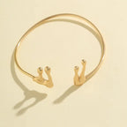 Gold bracelet with snail designs on a beige background