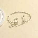 Silver bracelet with hook designs on a beige background