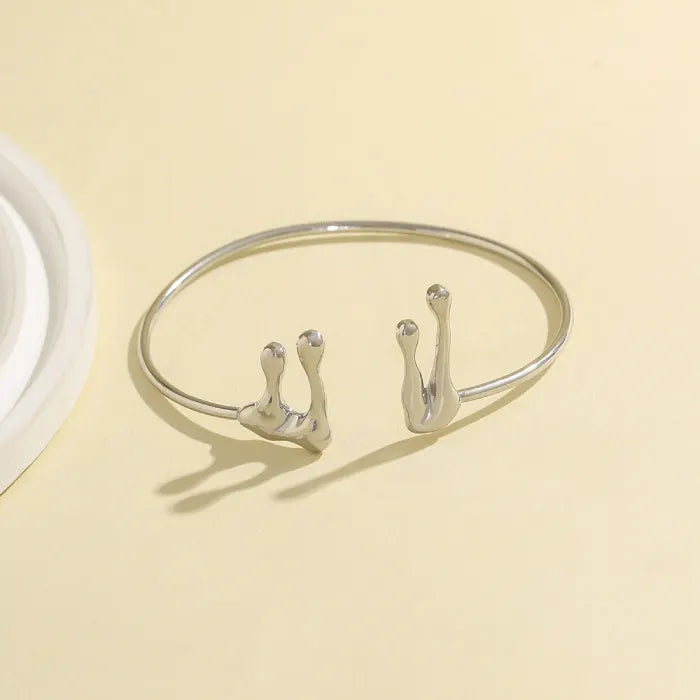 Silver bracelet with hook designs on a beige background