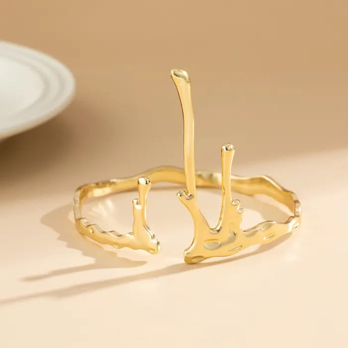 Gold branch-like bracelet on a beige background