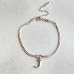 Silver bracelet with a letter 'J' charm on a light gray background