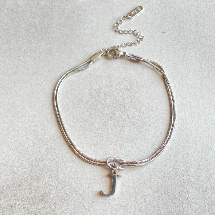 Silver bracelet with a letter 'J' charm on a light gray background