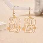 Gold New Year 2025 earrings displayed on white jewelry stand against neutral background