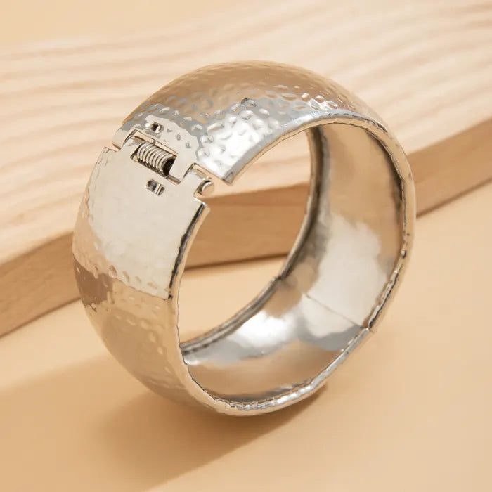 Silver ring with textured design on a beige background