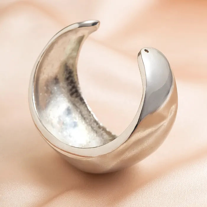 Silver ring shaped like a crescent moon on a soft beige background