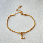 Gold bracelet with a letter 'L' charm on a light gray background