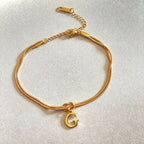 Gold bracelet with a 'G' charm on a light gray background