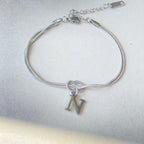 Silver bracelet with a 'NV' charm on a light gray background