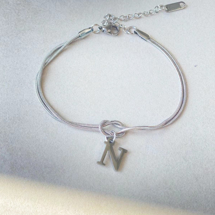 Silver bracelet with a 'NV' charm on a light gray background