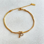 Gold bracelet with a letter 'P' charm on a light gray background